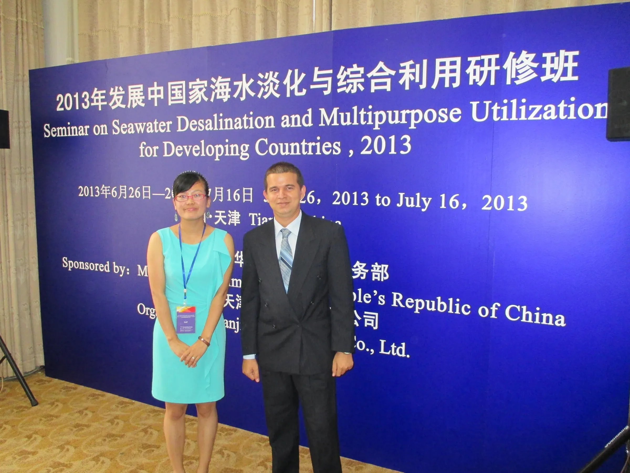 Lázaro Batule, de traje, posa junto al panel del Seminario sobre Desalinización de Agua de Mar para Países en Desarrollo, celebrado en Tianjin (China) en 2013, acompañado por otra persona del evento.